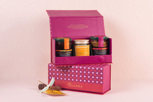 Pink gift box with Aamra  honey and candle products on a pink background