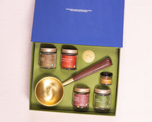 Spice jars and a brass spoon in a green box with a blue lid 
