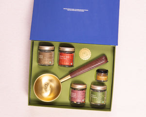 Spice jars and a brass spoon in a green box with a blue lid 