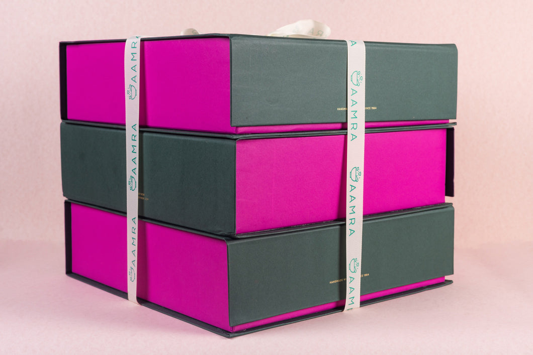 Stack of pink and green boxes with a measuring tape on a pink background