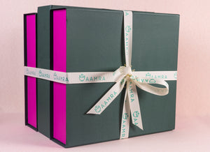 Green gift box with pink accents and a white ribbon on a light pink background