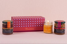 Three jars of honey and a lit candle on a pink background with 'Aamra' branding.